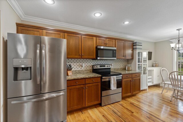 7083 Blue Springs Rd SE, Cleveland, TN 37311 - kitchen featuring appliances with stainless steel finishes, brown cabinets, ornamental molding, light wood finished floors, and a chandelier