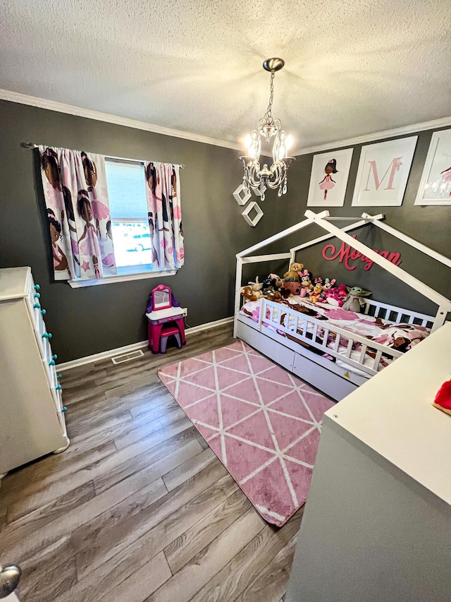 bedroom with visible vents, a textured ceiling, wood finished floors, a chandelier, and baseboards