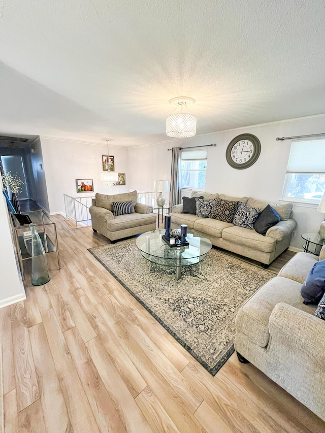 living room with plenty of natural light, a textured ceiling, light wood-type flooring, and baseboards