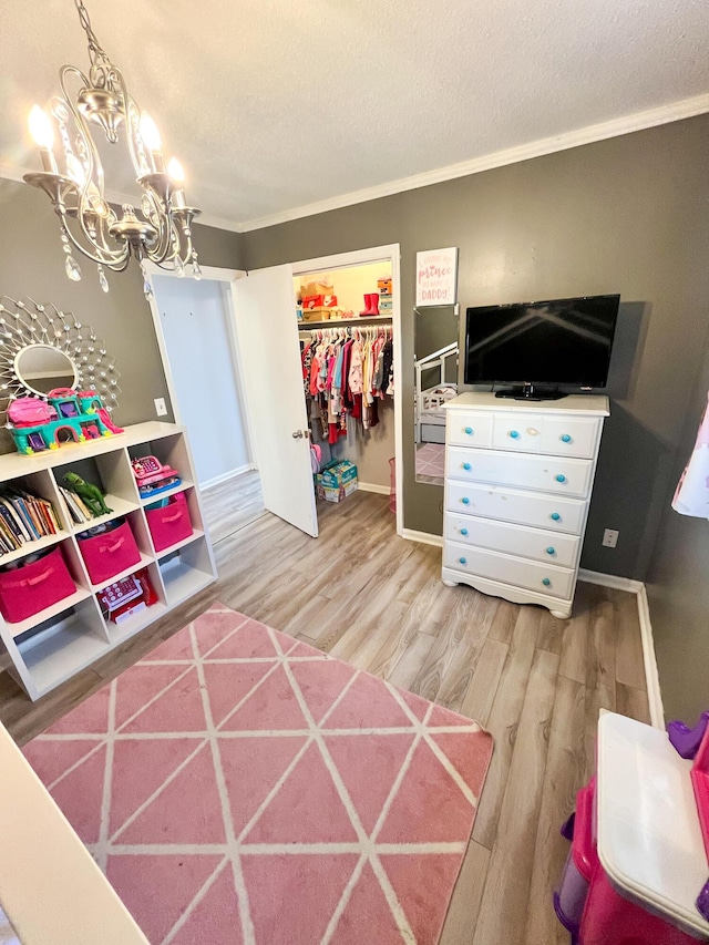 bedroom featuring crown molding, a textured ceiling, light wood-type flooring, a chandelier, and a closet