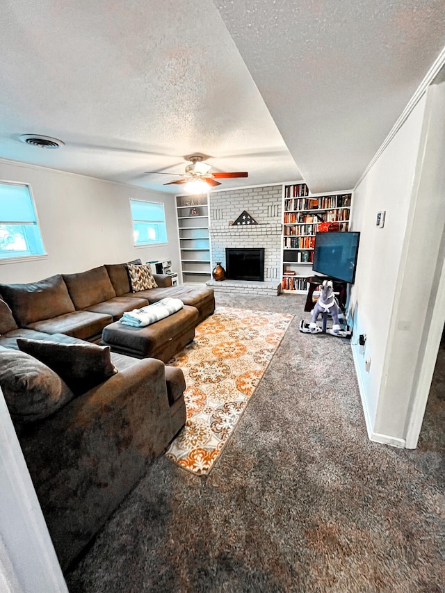 carpeted living area featuring a textured ceiling, built in shelves, visible vents, baseboards, and a brick fireplace