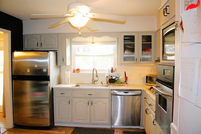 kitchen featuring glass insert cabinets, appliances with stainless steel finishes, light countertops, and a sink