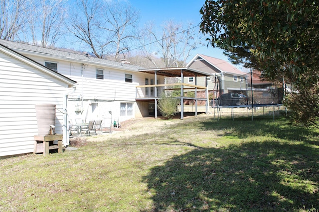 back of house featuring a trampoline and a lawn