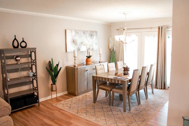 dining room featuring crown molding, a notable chandelier, baseboards, and wood finished floors