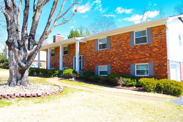 bi-level home with a front yard, a chimney, and brick siding