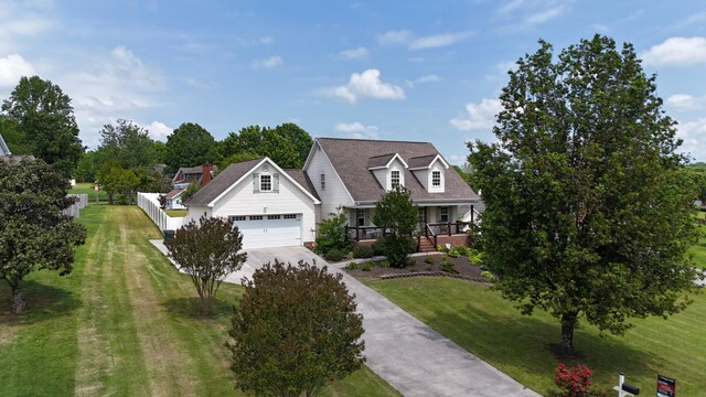 cape cod home featuring concrete driveway, a garage, covered porch, and a front lawn
