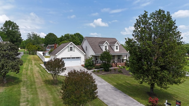 cape cod home featuring concrete driveway, a garage, covered porch, and a front lawn