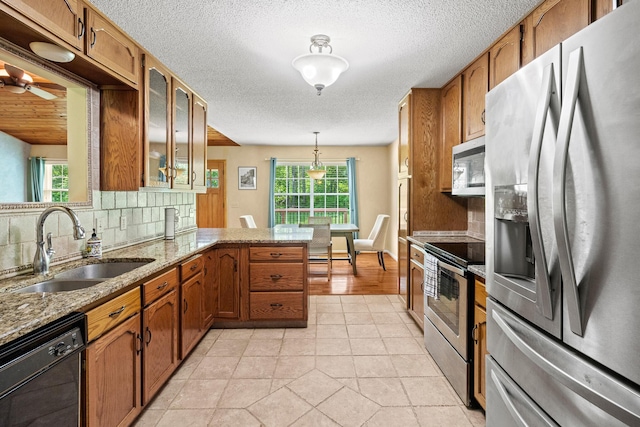 7510 Hewitt Ln, Chattanooga, TN 37421 - kitchen with appliances with stainless steel finishes, brown cabinets, a peninsula, decorative backsplash, and a textured ceiling