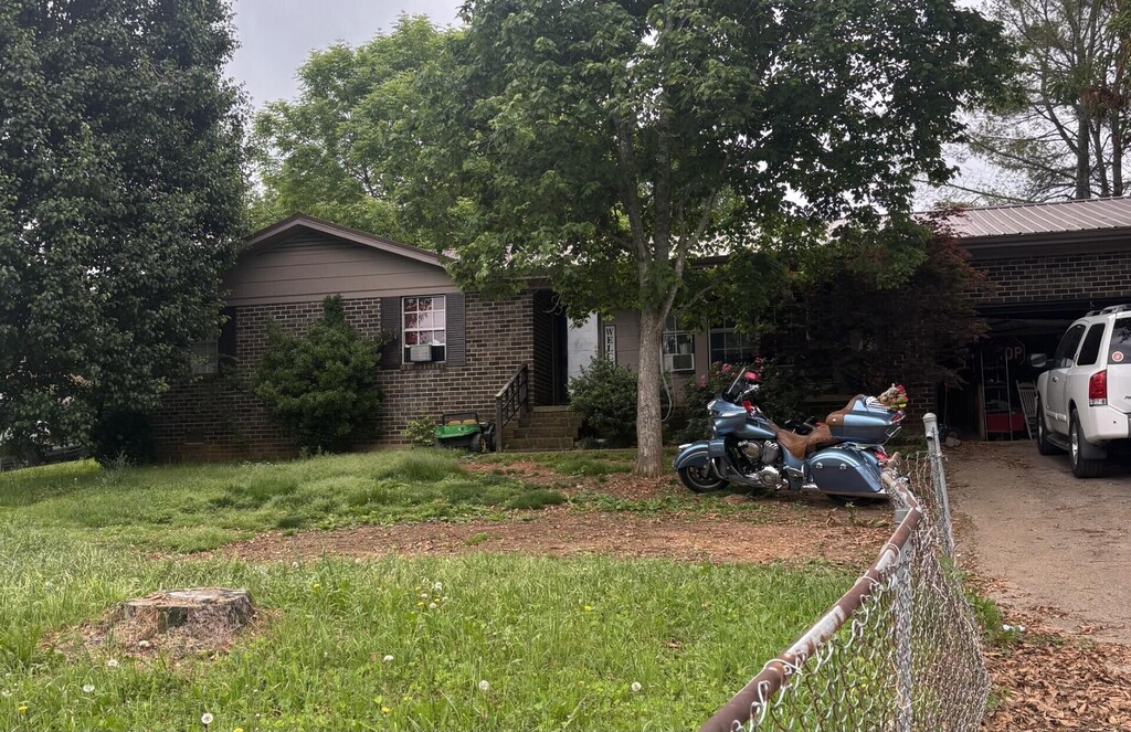 3715 Dockery St SE, Cleveland, TN 37311 - view of front of property featuring brick siding, fence, dirt driveway, and a carport