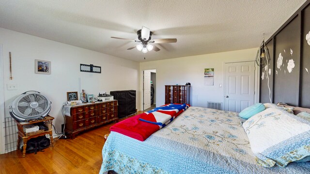 bedroom with ceiling fan, wood-type flooring, and a textured ceiling