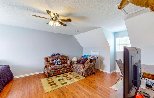 interior space with a textured ceiling, light wood-type flooring, ceiling fan, and lofted ceiling