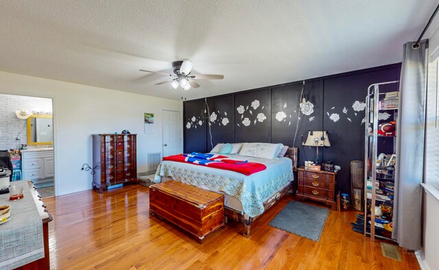 bedroom with connected bathroom, ceiling fan, a textured ceiling, and hardwood / wood-style flooring