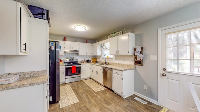 kitchen featuring appliances with stainless steel finishes, light wood-type flooring, a textured ceiling, sink, and white cabinets