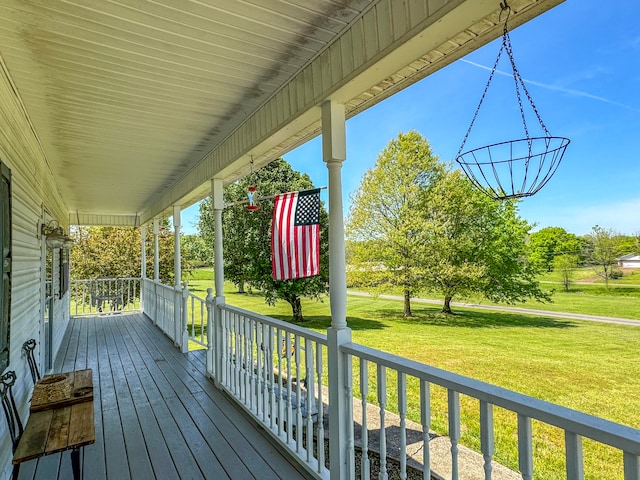 wooden terrace with a lawn and covered porch