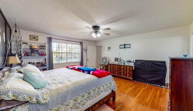 bedroom featuring ceiling fan, wood-type flooring, and a textured ceiling