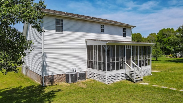 back of property with a sunroom, central air condition unit, and a lawn