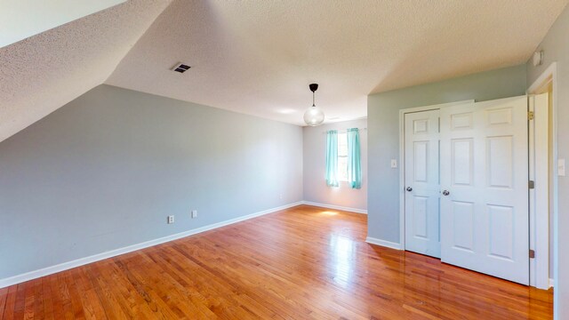 interior space with hardwood / wood-style floors, a textured ceiling, vaulted ceiling, and a closet