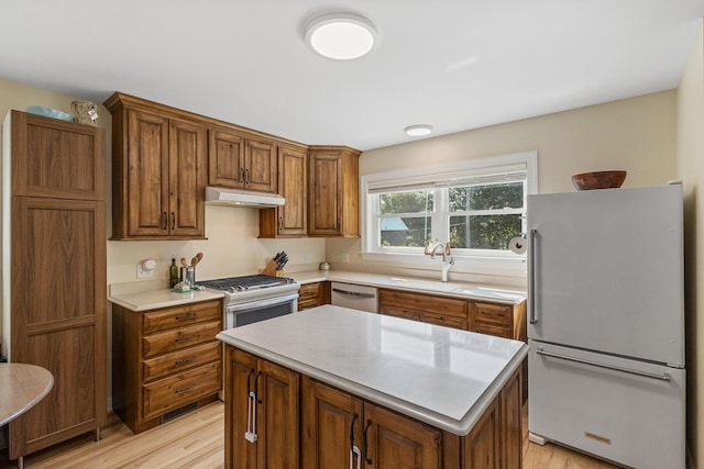 101 Riverview Ln, Reliance, TN 37369 - kitchen featuring white appliances, under cabinet range hood, light wood-type flooring, light countertops, and brown cabinetry
