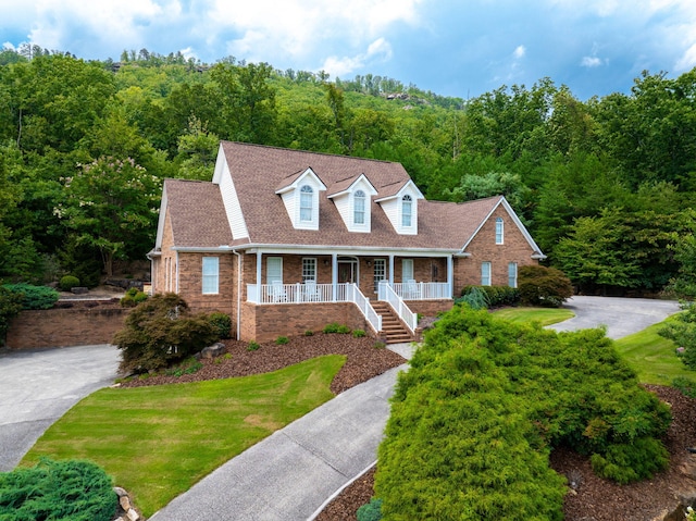 new england style home with covered porch and a front lawn