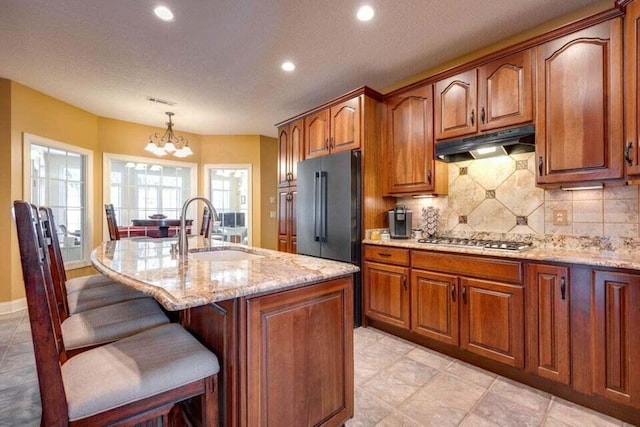 kitchen with sink, appliances with stainless steel finishes, decorative light fixtures, a kitchen bar, and a chandelier