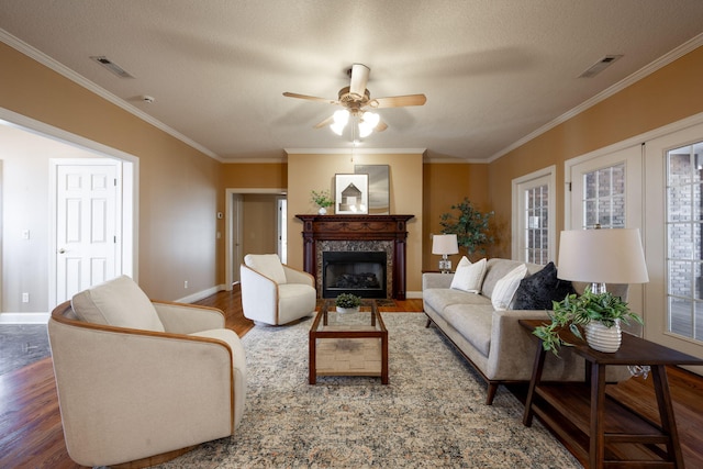 living room featuring a high end fireplace, dark wood-type flooring, ceiling fan, and ornamental molding