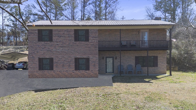 view of front of home with a front yard, brick siding, metal roof, and a balcony