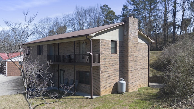 rear view of house with brick siding, metal roof, and a chimney