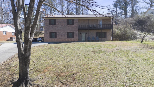 view of front of home featuring brick siding, a chimney, a front yard, and a balcony