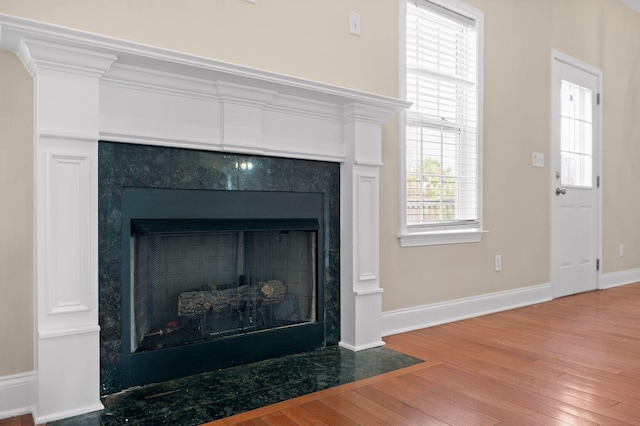 interior details featuring a fireplace with flush hearth, baseboards, and wood finished floors