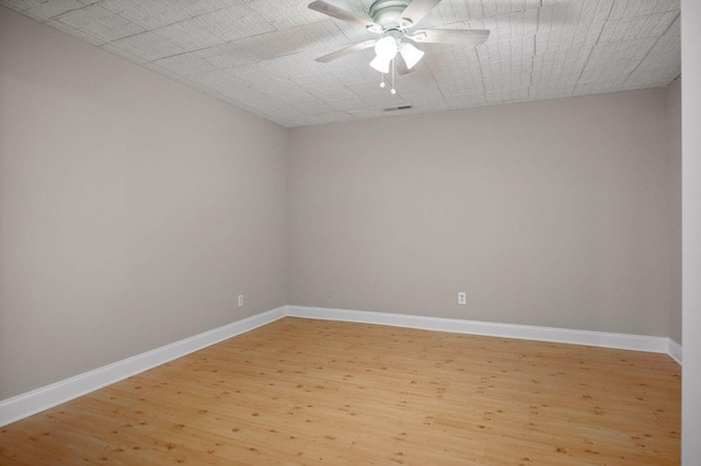 empty room with ceiling fan, light wood-type flooring, visible vents, and baseboards