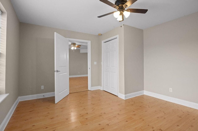 unfurnished bedroom featuring ceiling fan, a closet, light wood-style flooring, and baseboards