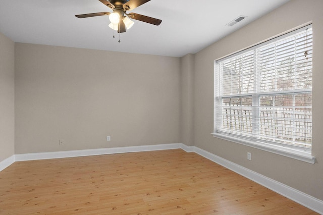 empty room featuring baseboards, a ceiling fan, visible vents, and light wood-style floors