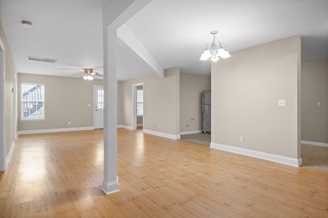 unfurnished living room featuring light wood-type flooring, visible vents, baseboards, and ceiling fan with notable chandelier