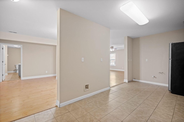 empty room with ceiling fan, baseboards, and light tile patterned flooring