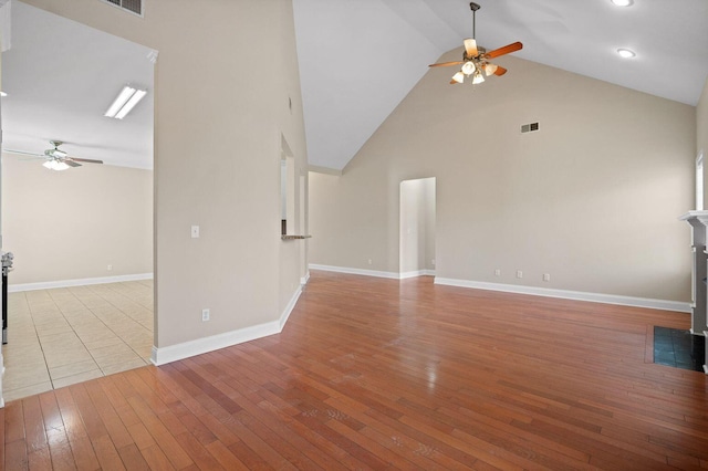 unfurnished living room featuring high vaulted ceiling, visible vents, baseboards, a ceiling fan, and hardwood / wood-style floors