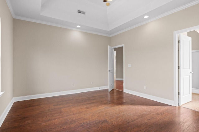 spare room featuring baseboards, visible vents, a raised ceiling, and wood finished floors