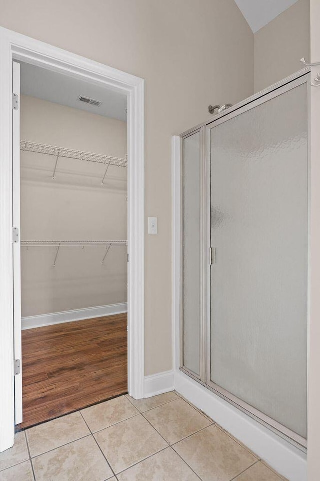 full bath with visible vents, baseboards, a spacious closet, tile patterned floors, and a stall shower