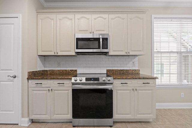 kitchen featuring crown molding, tasteful backsplash, appliances with stainless steel finishes, dark stone counters, and baseboards