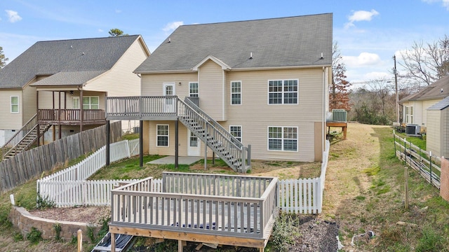 back of property with central AC unit, a fenced backyard, stairway, a deck, and a yard