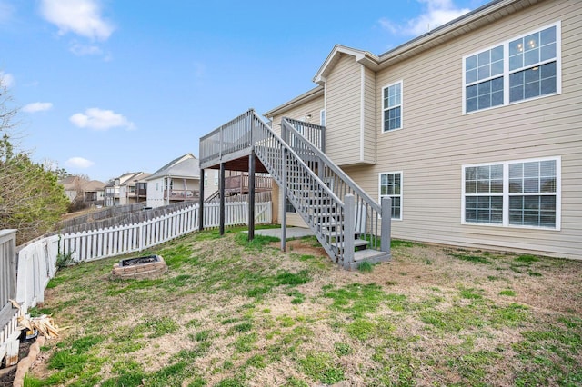 back of house featuring an outdoor fire pit, a lawn, a fenced backyard, stairway, and a wooden deck