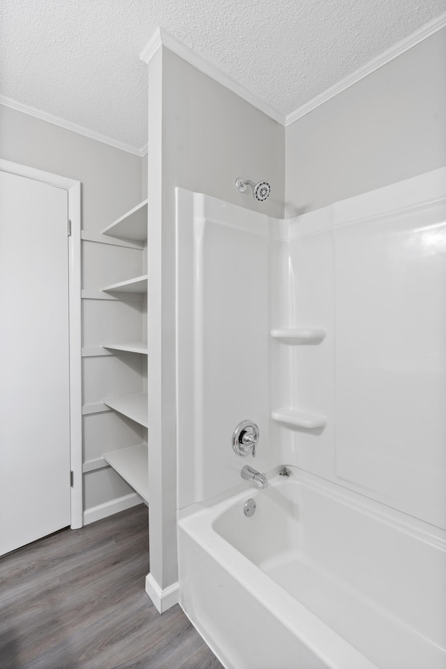 bathroom featuring crown molding, wood-type flooring, bathtub / shower combination, and a textured ceiling