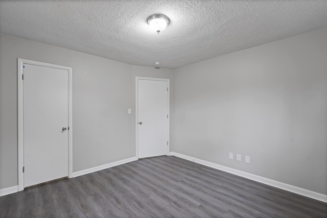 empty room with dark hardwood / wood-style floors and a textured ceiling