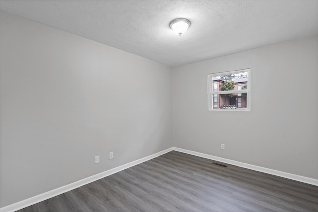 unfurnished room featuring dark hardwood / wood-style flooring and a textured ceiling