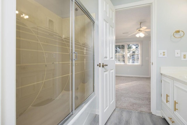 full bathroom with bath / shower combo with glass door, vanity, baseboards, and wood finished floors