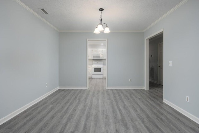 spare room with a textured ceiling, a notable chandelier, wood finished floors, visible vents, and baseboards