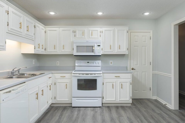 kitchen featuring light wood-style floors, white appliances, white cabinets, and a sink