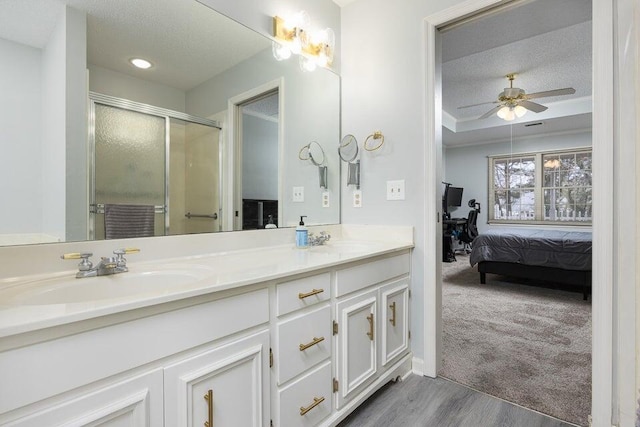 full bath featuring double vanity, a stall shower, a sink, a textured ceiling, and ensuite bath