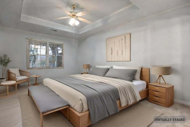 bedroom featuring a raised ceiling, light colored carpet, ornamental molding, ceiling fan, and baseboards