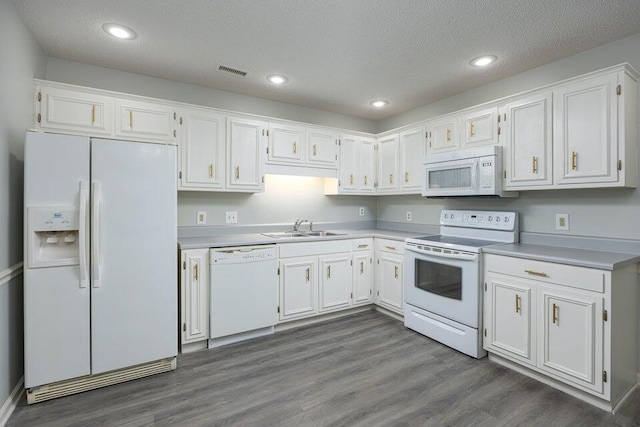 kitchen with white appliances, white cabinetry, a sink, and visible vents