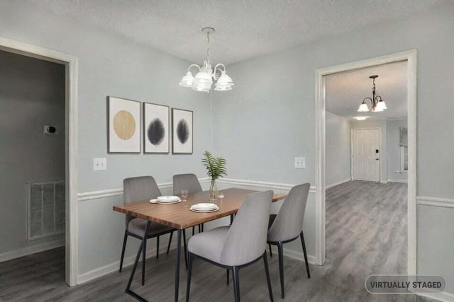 dining area featuring visible vents, an inviting chandelier, a textured ceiling, wood finished floors, and baseboards